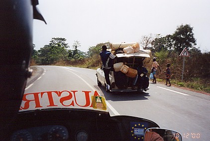 Overloaded car, note people hanging on the outside and travelling in the trunk