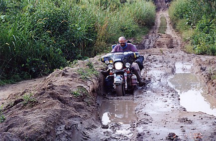 The Harley and Peter riding the muddy roads of the Congo.