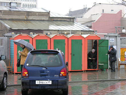 Lady waits out of the rain at one of her toilets, selling a spot for 5 Rubles, there are many around town