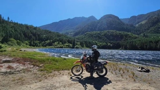 Chris Bragg, On motorcycle next to a river.